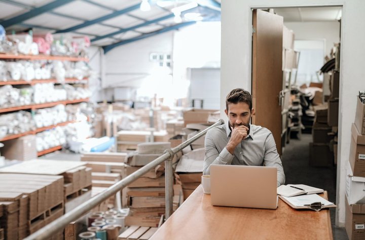 E-commerce professional working on a laptop in the warehouse to manage returns integration.