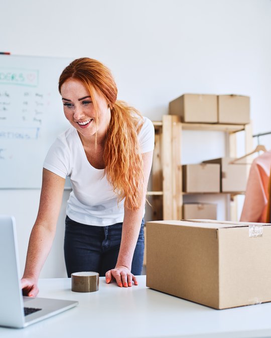 E-commerce business owner preparing parcels for shipment in warehouse.